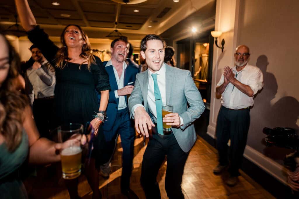 A man in a suit dancing at a wedding reception.