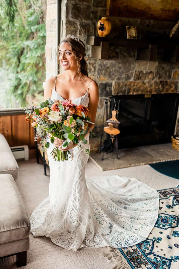 A bride holding her bouquet in front of a fireplace.