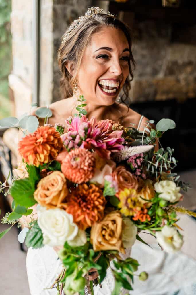 A bride laughs while holding her wedding bouquet.