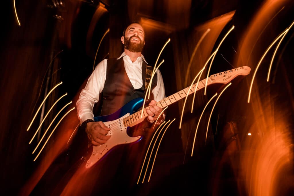 A man playing an electric guitar in a dark room.