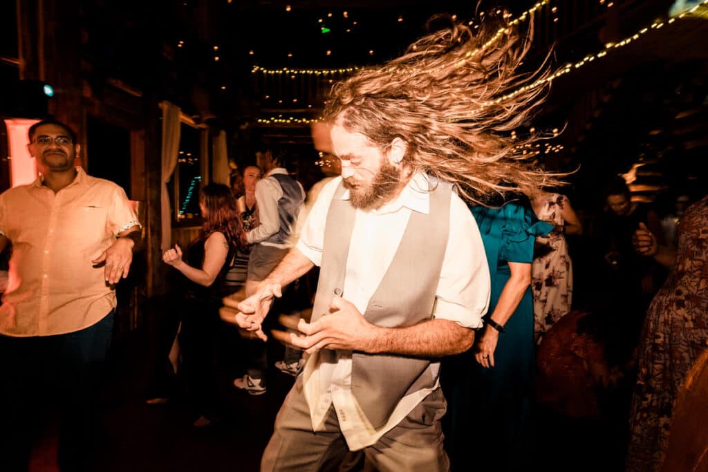 A man with long hair dancing at a party.