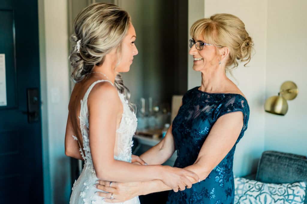 A bride and her mother are getting ready in a hotel room.