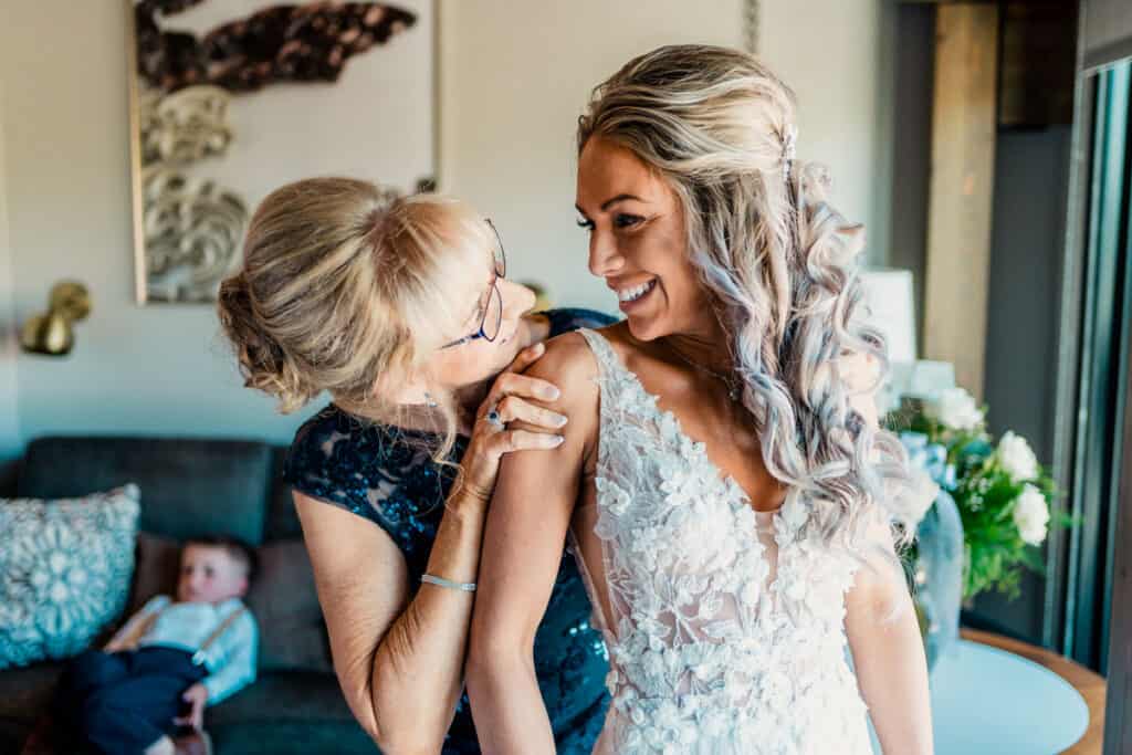 A mother helps her daughter put on her wedding dress.