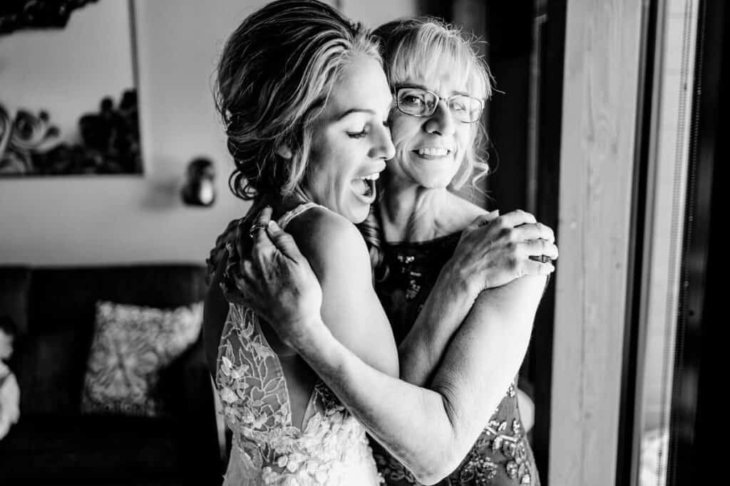 A black and white photo of a bride hugging her mother.