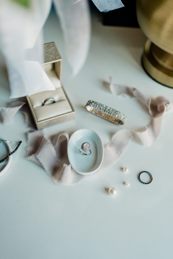 A wedding ring and other items on a white table.