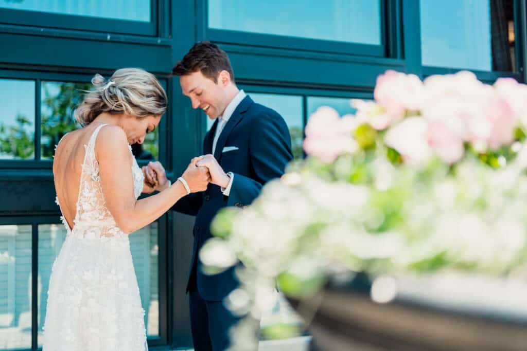 A bride and groom sharing a kiss in front of a window.