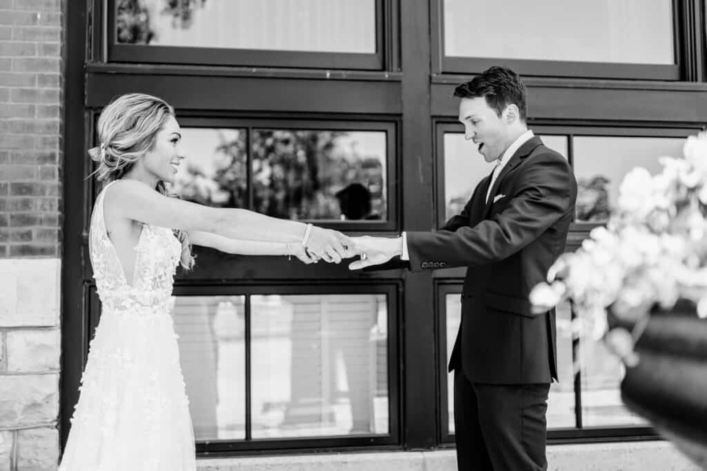 A bride and groom shaking hands in front of a building.