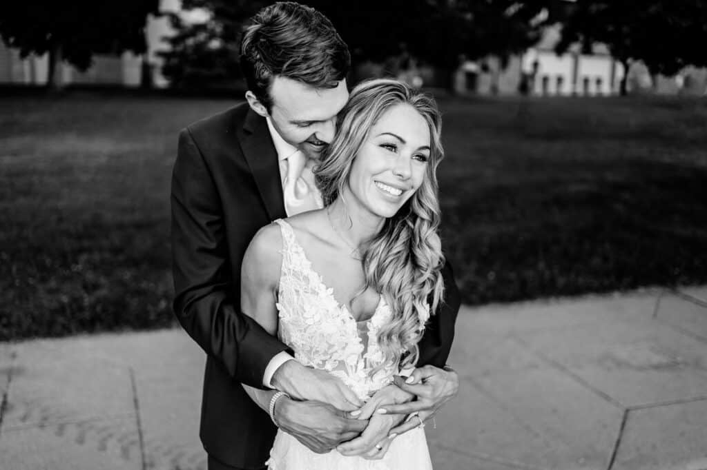 A black and white photo of a bride and groom hugging.