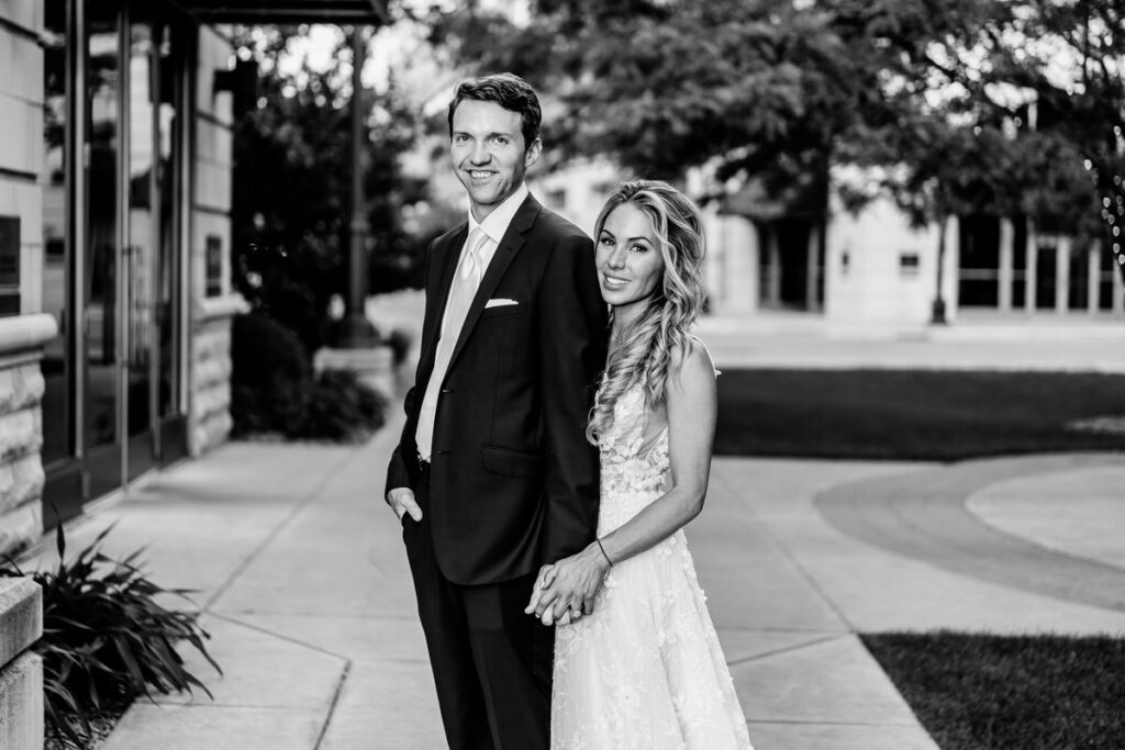 A black and white photo of a bride and groom in front of a building.