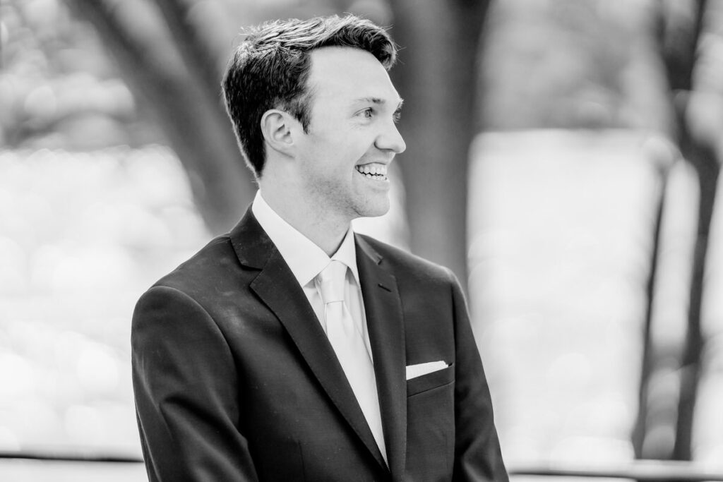 A black and white photo of a groom smiling.