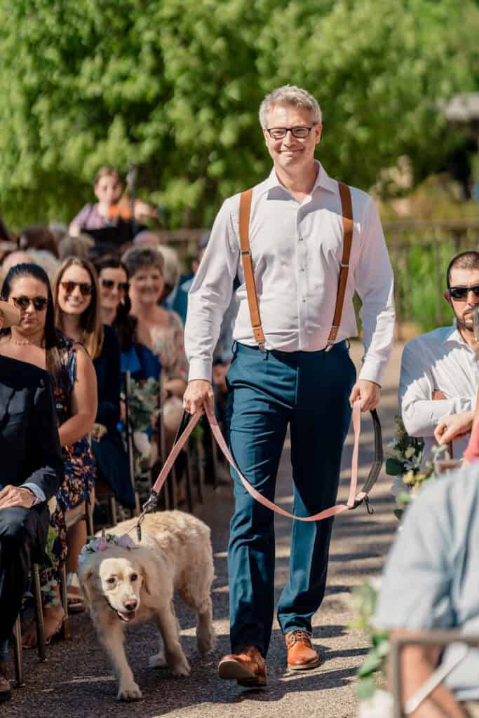 A man walking his dog down the aisle at a wedding.