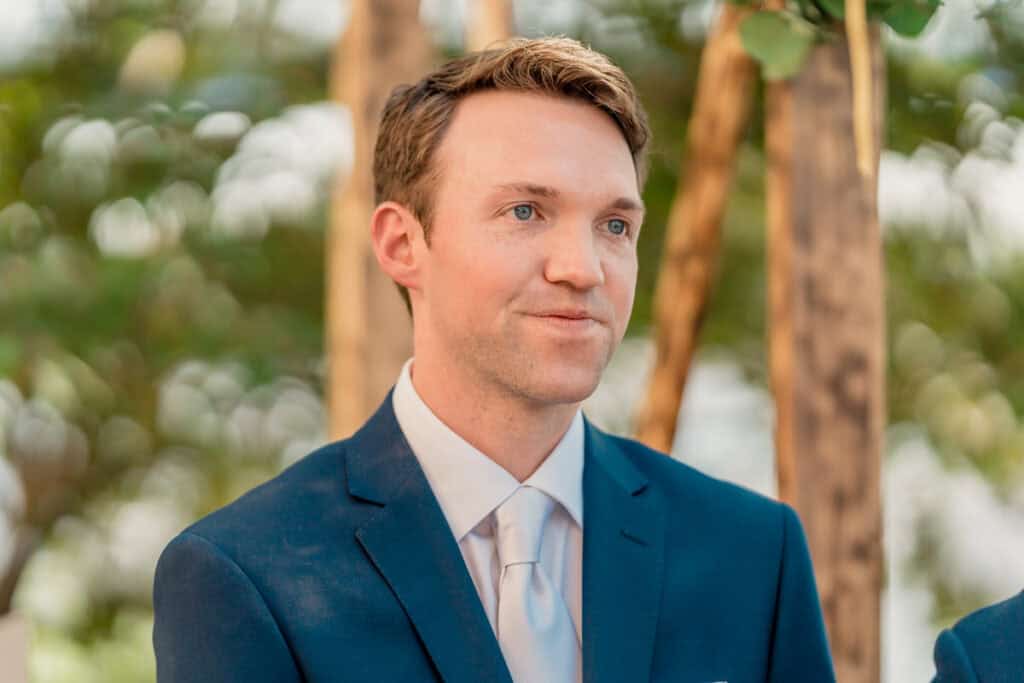 A man in a suit and tie looks at his bride.