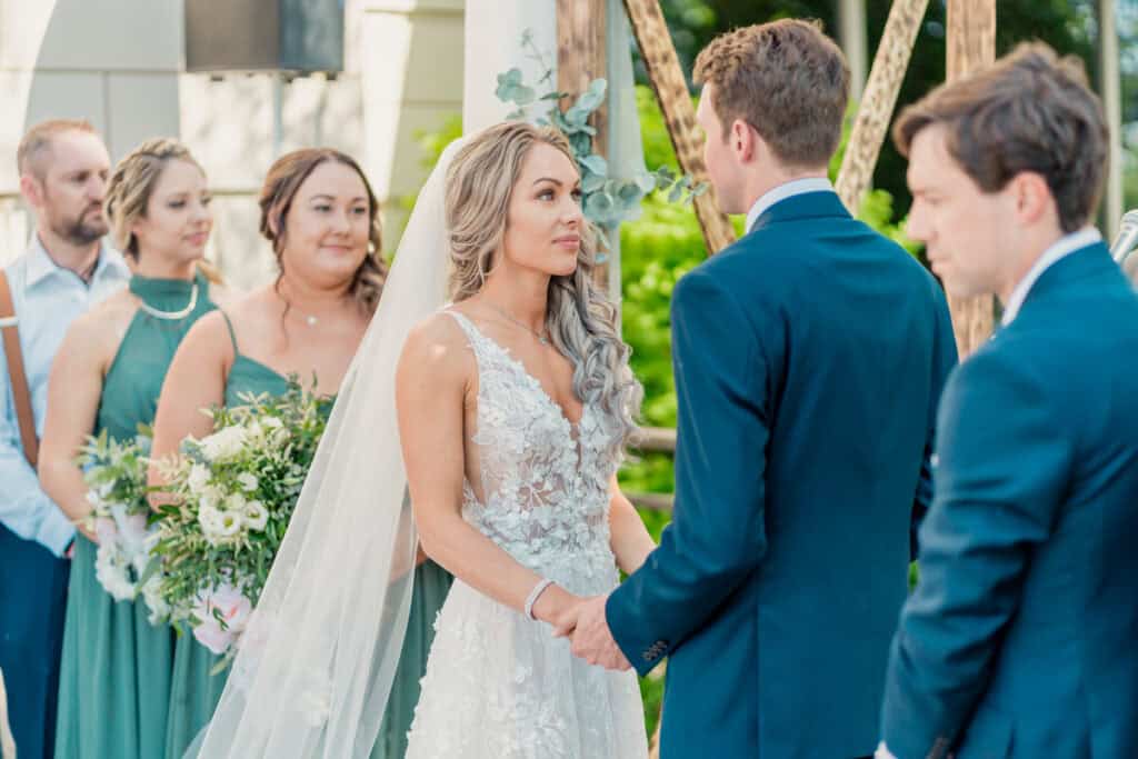 A bride and groom exchange vows in front of their wedding party.