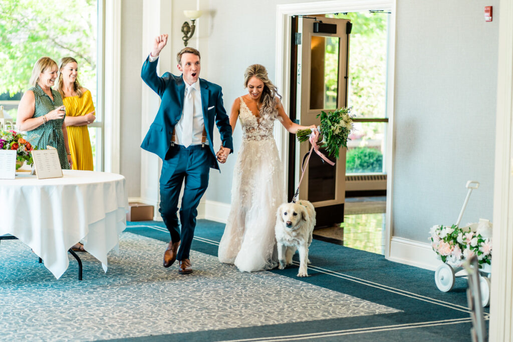 A bride and groom with their dog walking down the aisle.
