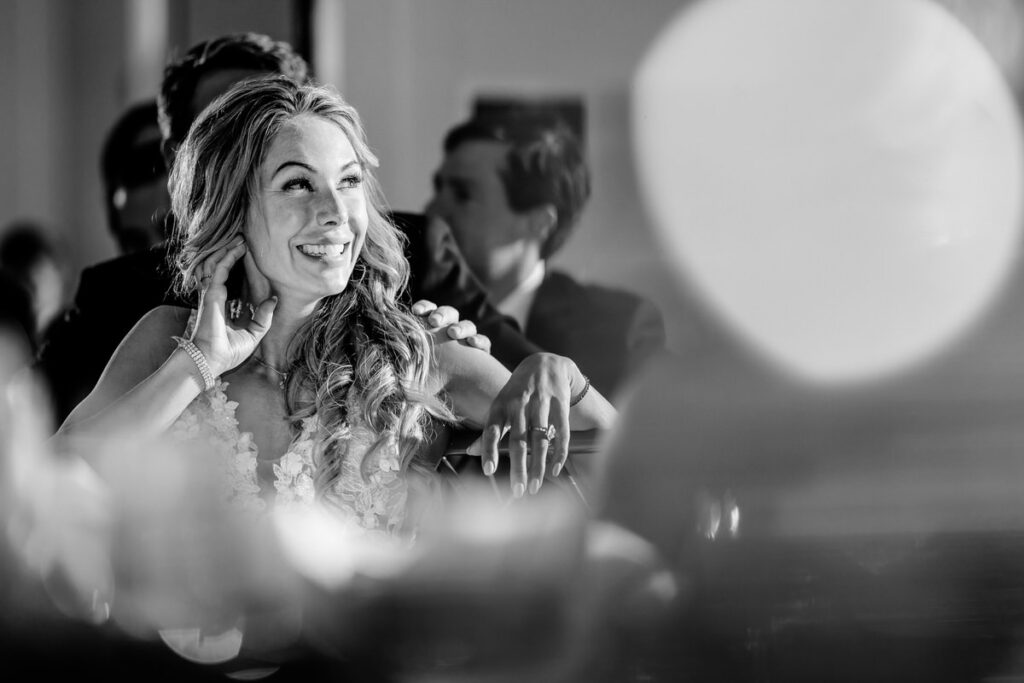 A black and white photo of a woman laughing at a wedding reception.