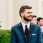 Groom and groomsmen smiling in front of a church.