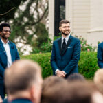 A group of groomsmen standing in front of a church.