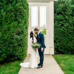 A bride and groom kissing in front of a gate.