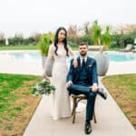 A bride and groom posing in front of a pool.