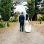 A bride and groom walking down a dirt path.