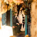 A bride and groom are posing in front of a mirror.