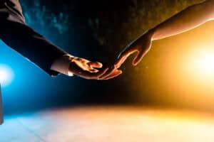 A man and woman holding hands in front of a bright light.