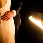 A bride and groom hugging in front of a fireplace.