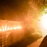 A bride and groom kissing in front of a fire.