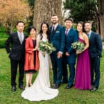 A wedding party posing in front of a tree.