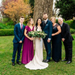 A wedding party posing for a photo in front of a tree.