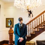 A bride and groom standing on the stairs of a mansion.