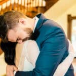 A bride and groom hugging in front of a staircase.