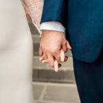 A bride and groom holding hands on steps.
