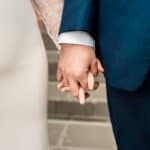 A bride and groom holding hands on steps.