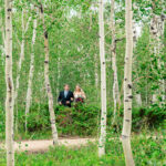 A bride and groom walking through a forest of aspen trees.
