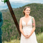 A bride and groom stand in front of a mountain during their wedding ceremony.