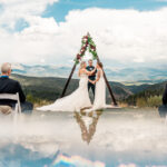 A wedding ceremony in the mountains with clouds in the background.