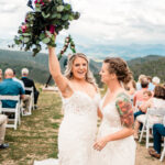 Two brides walk down the aisle at a mountain wedding ceremony.