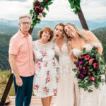 A bride and her family pose for a photo in the mountains.