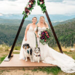 Two brides and their dogs at a mountain wedding.