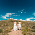 Two brides walking down a hill in a white dress.
