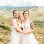 Two brides posing for a photo in the mountains.