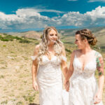 Two brides walking in the mountains on their wedding day.