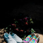 A pair of colorful vans slip ons sitting on a stone.