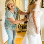 A woman helping her daughter put on her wedding dress.