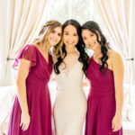 Three bridesmaids posing for a photo in burgundy dresses.