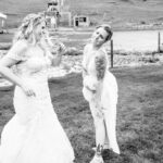 Two brides in their wedding dresses playing in the grass.