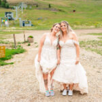 Two brides posing in front of a ski lift.