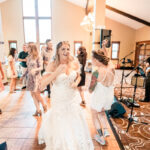 A bride and her bridesmaids dancing at a wedding reception.