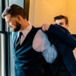 A man in a suit is putting on his jacket.